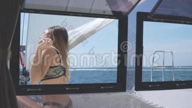 一个漂亮的女孩坐在游艇甲板上。 透过窗户观看。